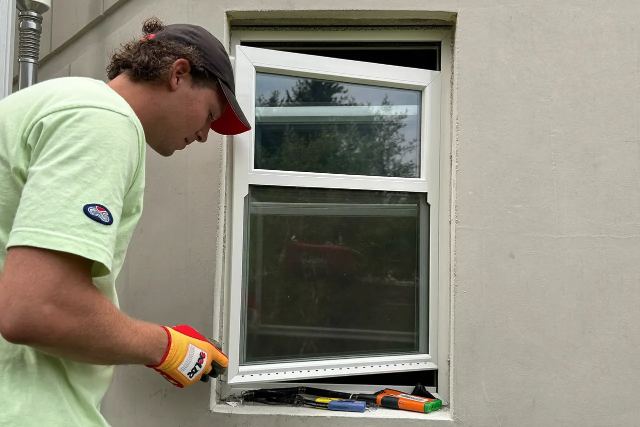 Local installer fitting a replacement window on a residential street